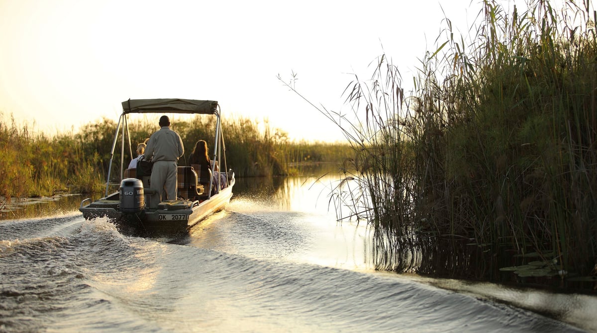 Botswana-andBeyondNxabega-Okavango-Delta-Camp-Exerience-Boat-cruise-boat-on-right-at-sunset
